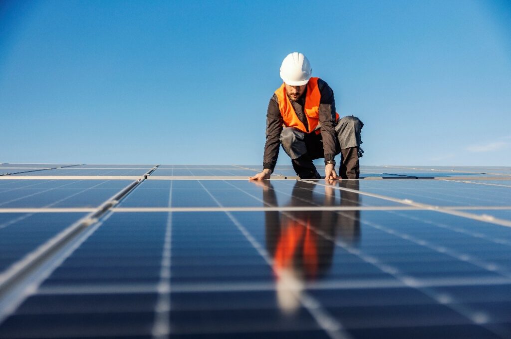 A handyman installing solar panels on the rooftop.